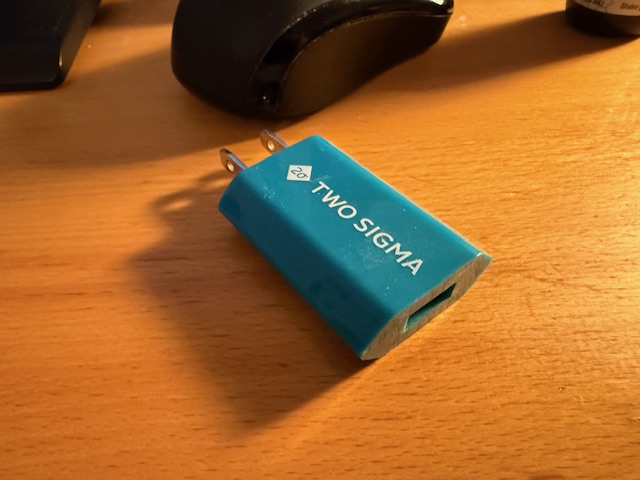 Photo of a teal hexagonal USB to wall power adapter. On the top reads "TWO SIGMA".